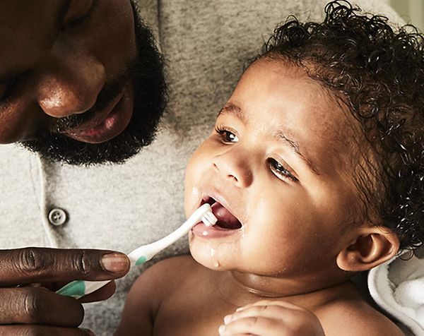 Father brushing babies teeth